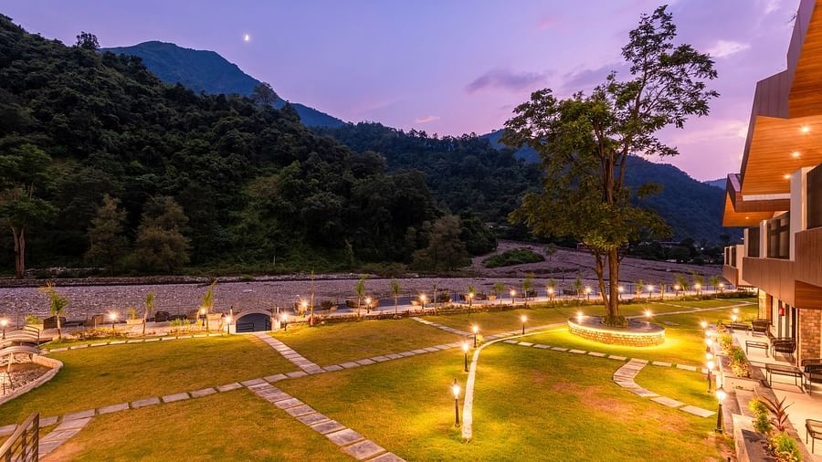 Closeup view of garden area at DLS Divine River Resort and Spa featuring lush green grass and flower pots taken during night.