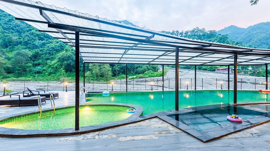 A swimming pool at DLS Divine Resort and Spa with serene views and kids pool area.
