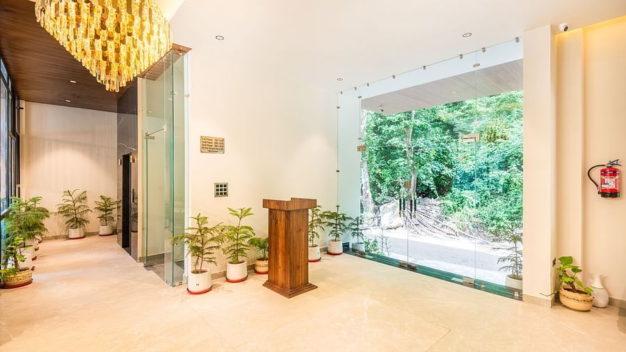 Close up view of reception area of DLS Divine River Resort and Spa featuring a grand chandelier a podium and plant pots.