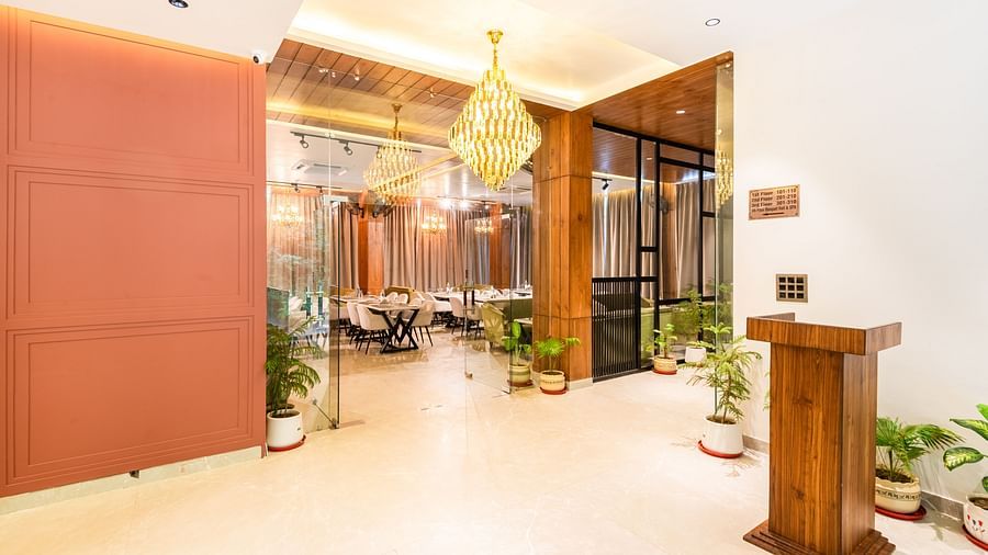 Reception area of DLS Divine River Resort and Spa featuring a grand chandelier a podium and plant pots.