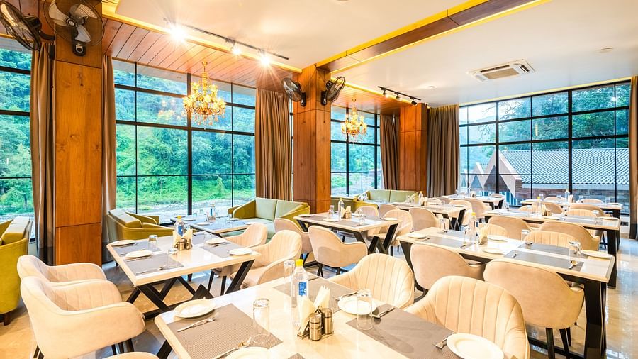 Restaurant at DLS Divine River Resort and Spa  with seating arrangement, large window, chandelier and ambient lighting. 