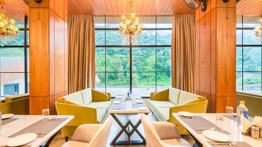 Restaurant at DLS Divine River Resort and Spa  with seating arrangement, large window, chandelier, and ambient lighting. 