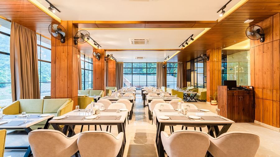 Restaurant at DLS Divine River Resort and Spa  with seating arrangement, large window and ambient lighting. 
