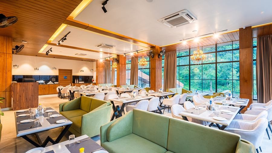 Restaurant at DLS Divine River Resort and Spa  with seating arrangement, large window, green sofa and ambient lighting. 