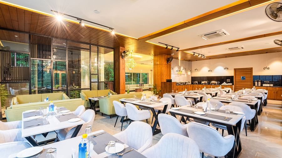 Restaurant at DLS Divine River Resort and Spa  with seating arrangement, large window and ambient lighting. 