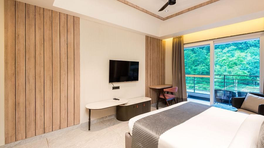 Deluxe Room at DLS Divine River Resort and  Spa featuring a  king bed , side table, TV and balcony with forest views.
