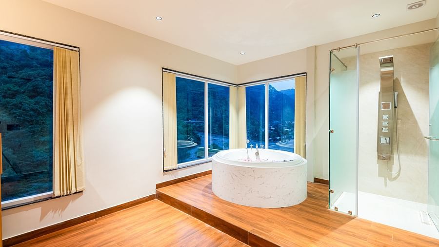 Overview of Jacuzzi at DLS Divine River Resort and Spa with flower petals floating in water and a huge window with serene views.