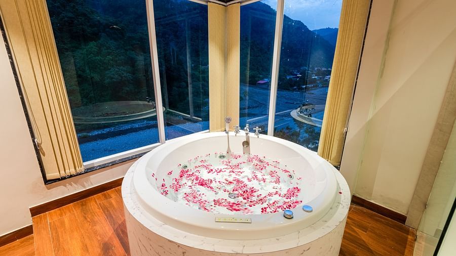 Jacuzzi at DLS Divine River Resort and Spa with flower petals floating in water and a huge window with serene views.