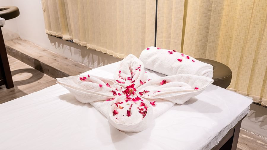 Closeup view of spa at DLS Divine Resort and Spa with towels and flower petals kept on the spa bed.