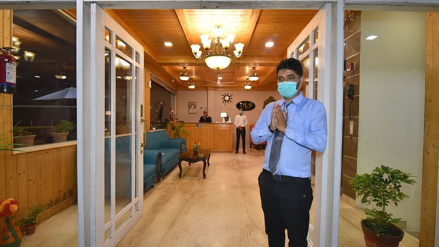 Reception area with a person welcoming the guests and two of the other hoteliers standing at the desk at DLS Highland Resort and Spa, Mussoorie.