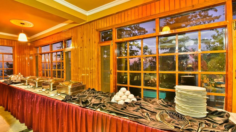 Close up view of buffet area with plates, bowls, and cutlery at DLS Hillcrest Resort, Shimla.