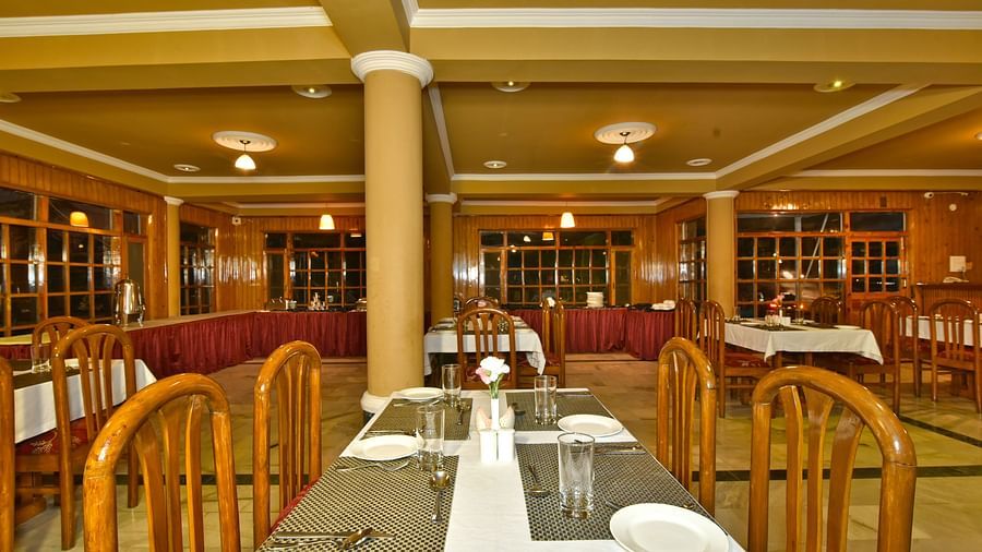 Dining space with wooden chairs and tables at DLS Hillcrest Resort, Shimla.
