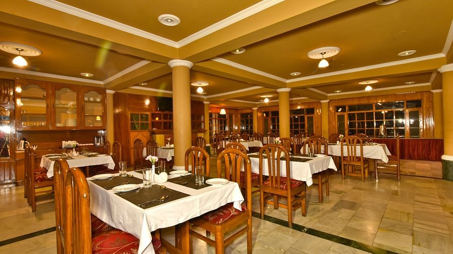 A cosy dining space with tables and chairs at DLS Hillcrest Resort, Shimla.