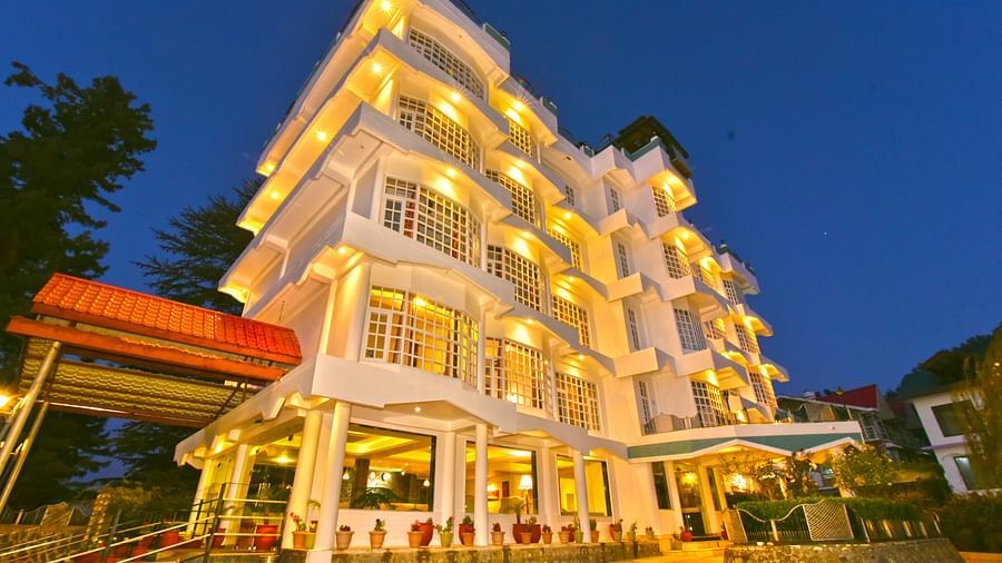 Exterior view of DLS Hillcrest Resort, Shimla, illuminated with warm yellow lights during the evening.