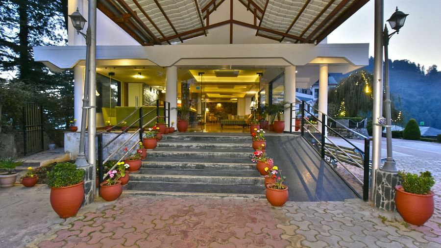 Entrance to the property with a lined walking path, adorned with potted plants on each side, at DLS Hillcrest Resort, Shimla.