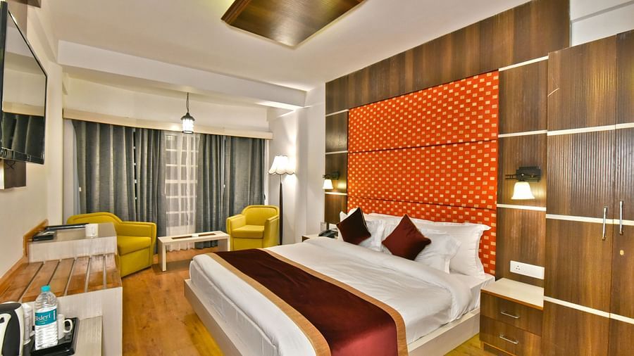 A bedroom with a tea and coffee maker and a seating area with chairs at DLS Hillcrest Resort, Shimla.