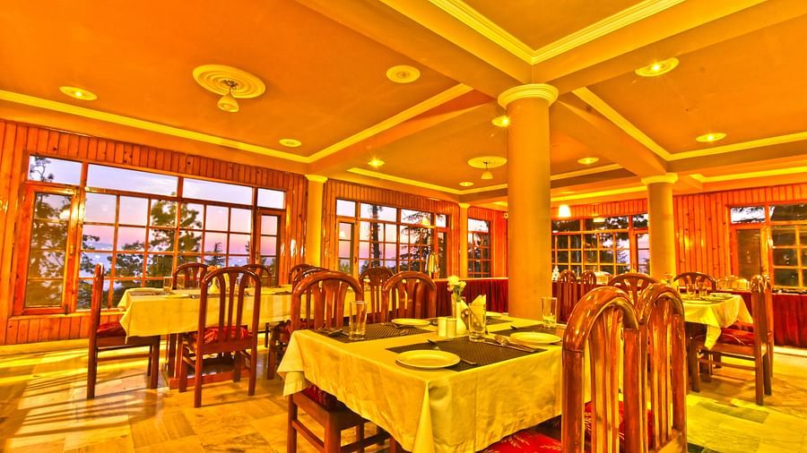 Restaurant with chairs, tables, and cutlery set up at DLS Hillcrest Resort, Shimla.
