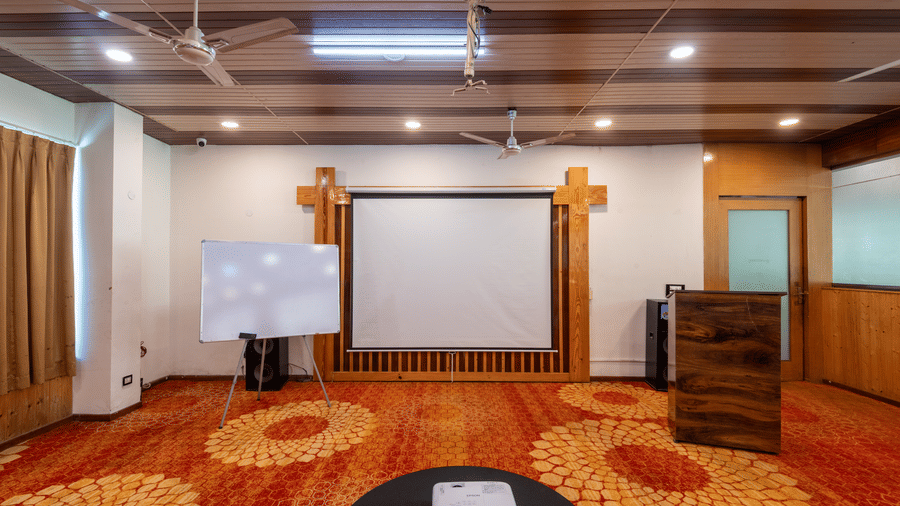 A detailed view of the banquet hall at DLS Hotels on the Ganges Rishikesh featuring long curtains wooden panelling and neatly arranged seating offering a polished and organised setup for events and conferences.
