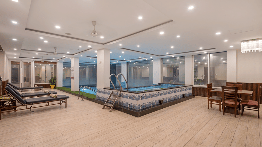 A spacious indoor poolside area at DLS Hotels on the Ganges Rishikesh offering dedicated lounging spaces warm lighting and a clean contemporary environment for guests to unwind and enjoy a peaceful swim.