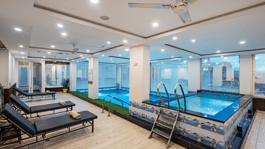 A stylish indoor pool at DLS Hotels on the Ganges Rishikesh with lounge chairs modern decor and a serene atmosphere providing a soothing retreat for guests looking to relax during their stay.