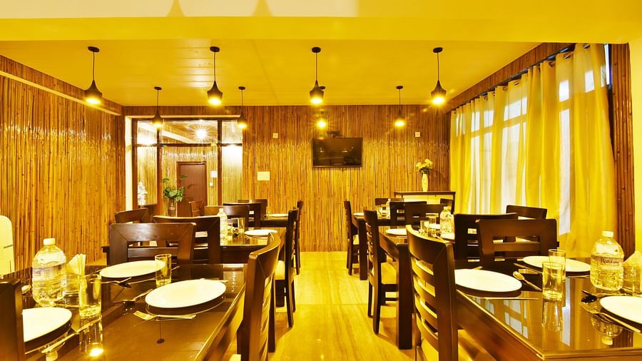 A wide angle shot of the dining area at the resort with woodden tables and chairs | DLS Kapoor Resort Manali