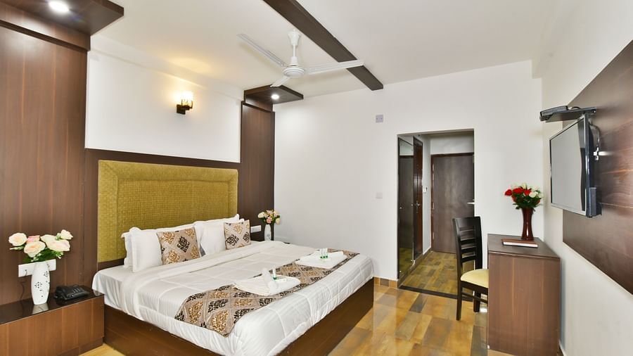 The spacious and well lit guest room that features a comfortable bed, a work desk, and a modern aesthetic | DLS Kapoor Resort Manali