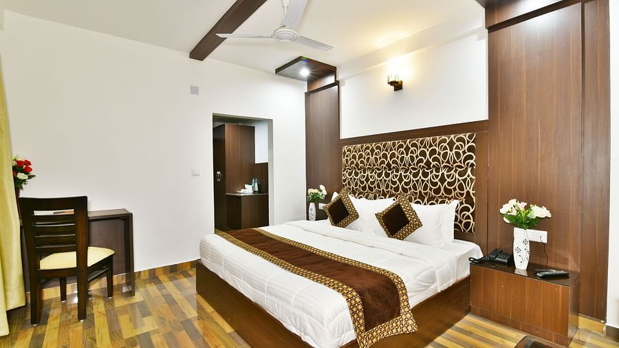 A wide angle shot of the room featuring king size bed, woodden flooring and wardrobe | DLS Kapoor Resort Manali