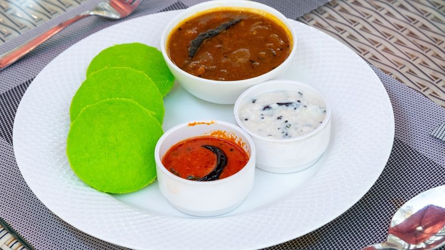 South Indian breakfast plate with three green idlis, served alongside bowls of sambar, coconut chutney, and tomato chutney on a white plate - DLS Nature Trinket Resort, Dalhousie.