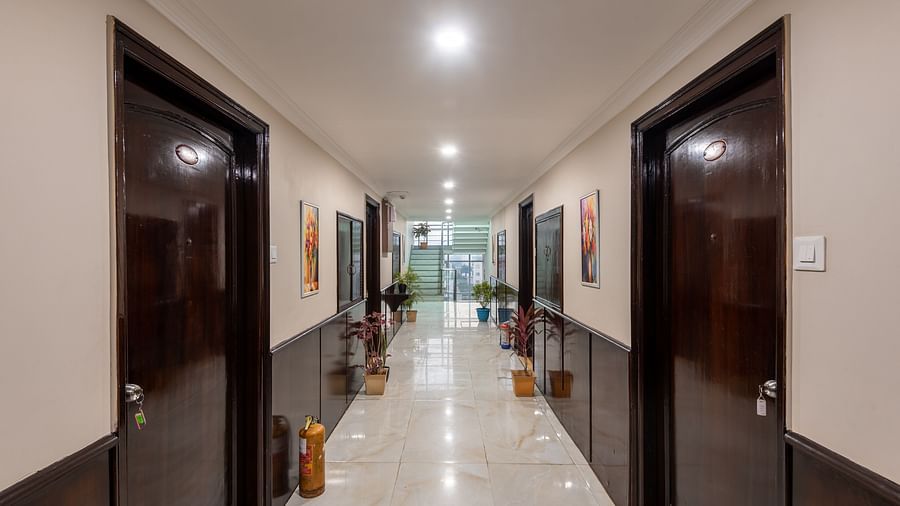 Corridor area at DLS Park Grace, Haridwar multiple doorways to hotel rooms, flight of chairs by the end and bright lighting.