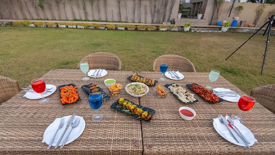 Outdoor dining space with tables and chairs on a grassy area at DLS Park Grace, Haridwar.