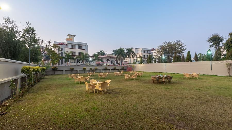 Lawn area with chairs and round tables at DLS Park Grace, Haridwar.