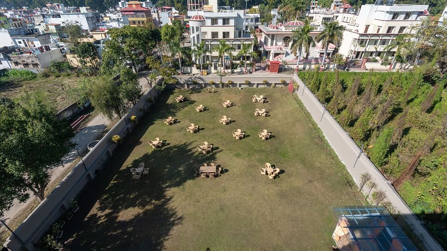 Aerial view of a lush green lawn encircled by tall trees at DLS Park Grace, Haridwar.