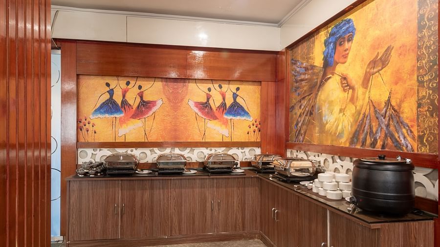 Buffet area at DLS Park Grace, Haridwar featuring  various food options, wall art and wooden furniture.