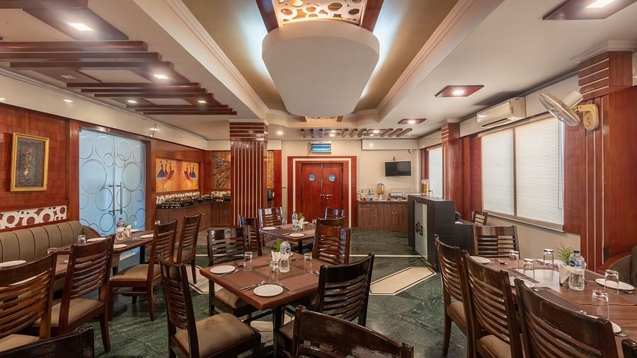 Dining area with a designed ceiling and wooden tables and chairs at DLS Park Grace, Haridwar.