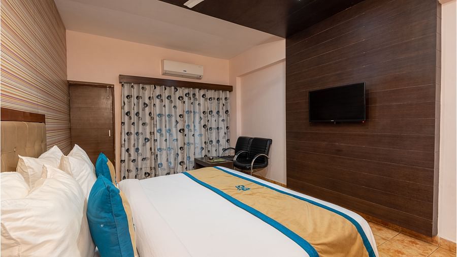 Side view of a Deluxe Non view room at DLS Spring Valley resort  Dharamshala featuring a  king bed, table, chairs and a TV