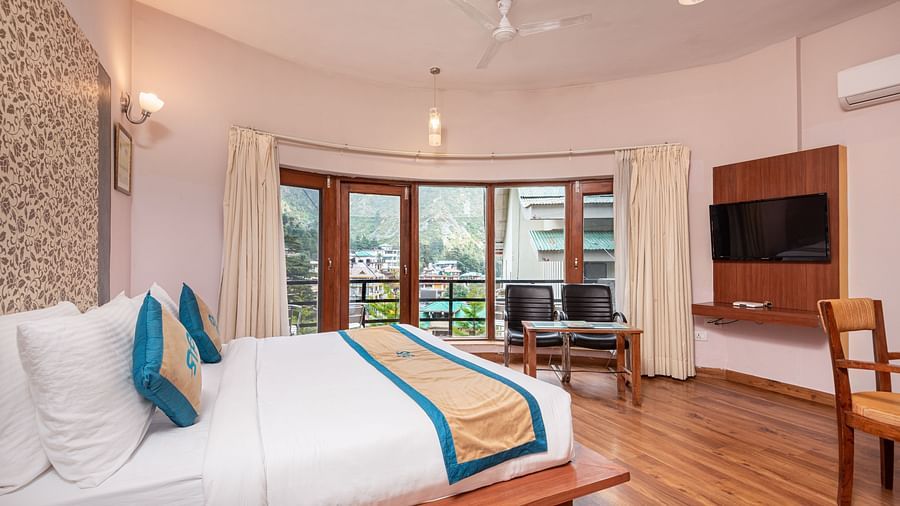 Side view Luxury Cottage at DLS Spring Valley Resort Dharamshala featuring a king size bed, table, TV, and a big balcony