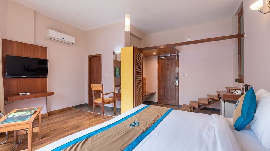 Side view of Luxury Cottage at DLS Spring Valley Resort Dharamshala featuring a king size bed, table, TV, and staircase