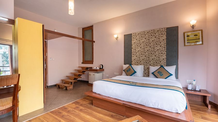 A Luxury Cottage at DLS Spring Valley Resort Dharamshala featuring a king size bed, table and staircase