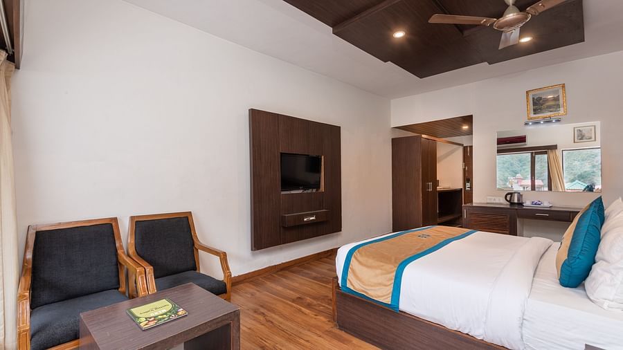 A Premium Room at DLS Spring Valley Resort Dharamshala featuring a king size bed, TV and a chairs