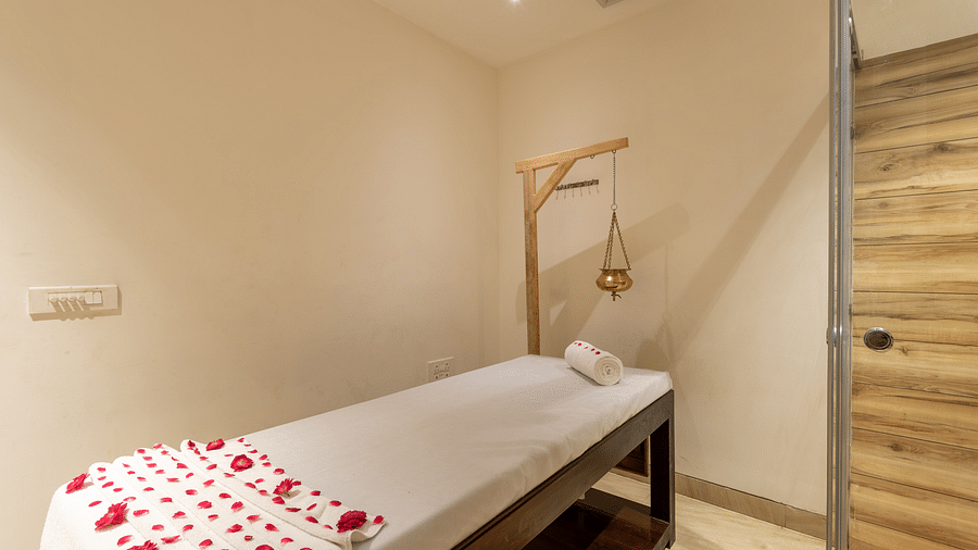 image of spa with a bed decorated with rose petals and a Shirodhara vessel at DLS The Classio