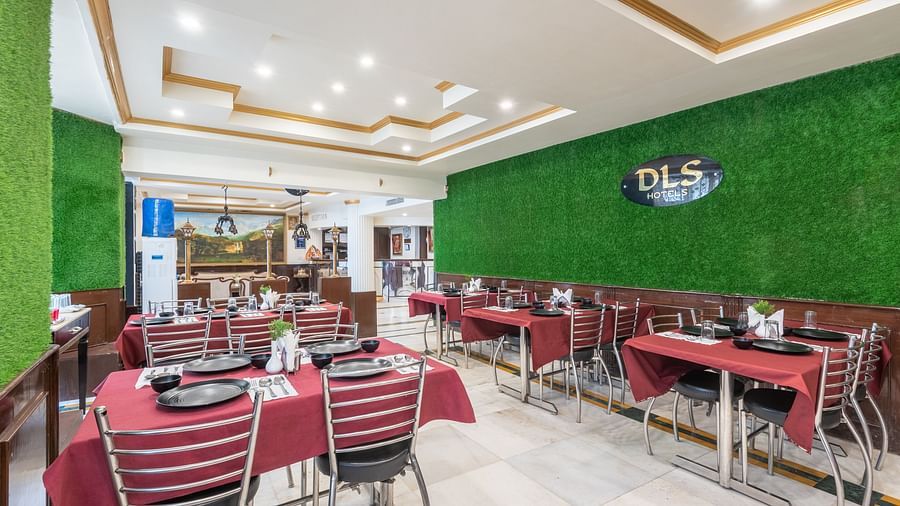 Image of dining area with red tablecloths, metal chairs, and a green wall | DLS The Pearl