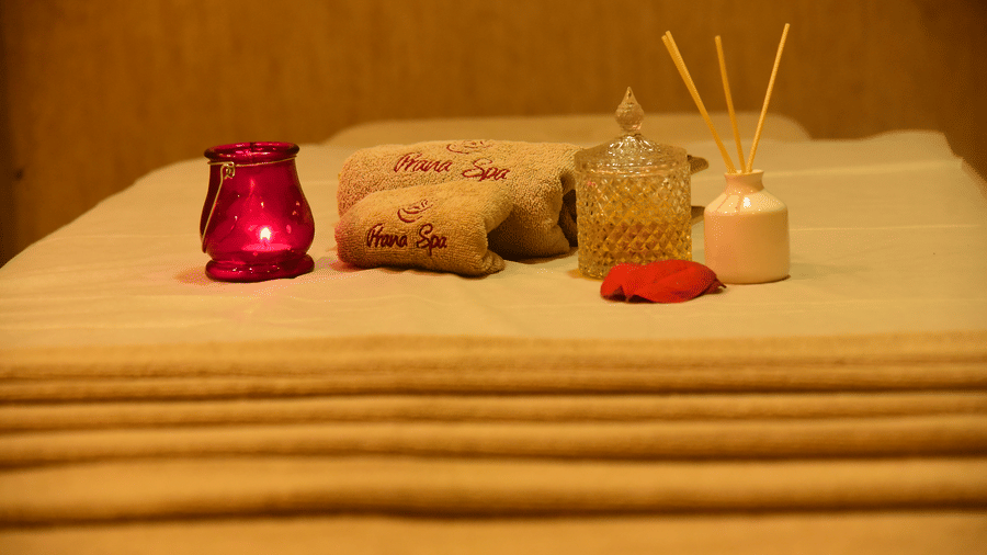 A serene spa setup at DNC Shevaroys Resort & Spa with folded linens, a decorative glass jar, and a candle holder on a treatment table.