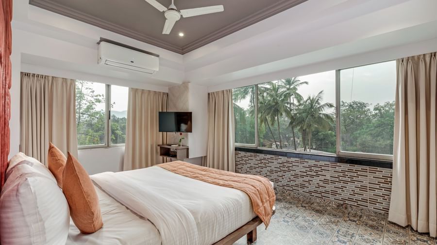 Spacious room at Emerald Retreat, Tungarli with a queen size bed, large windows, and calming garden views.