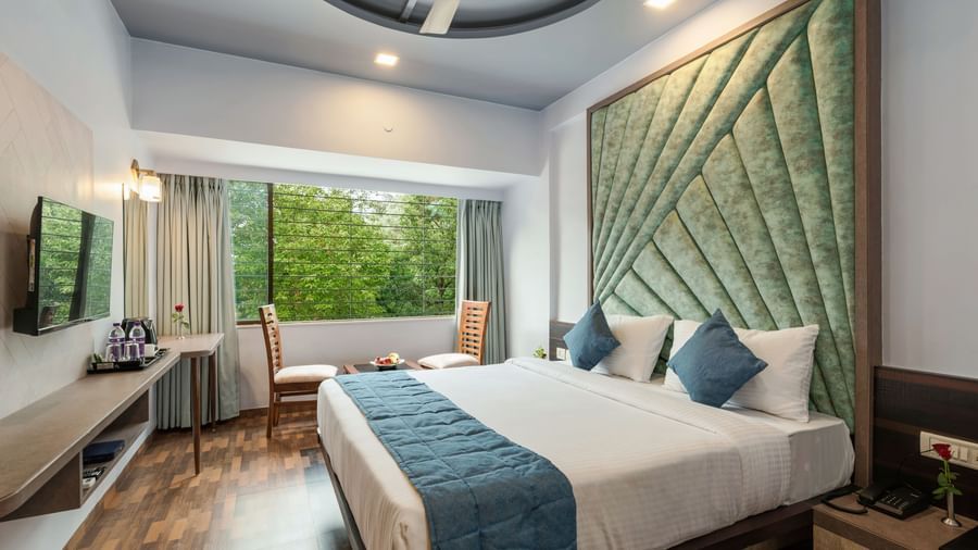Chic bedroom at Emerald Retreat, Tungarli with a velvet headboard, soothing tones, and garden-facing windows.