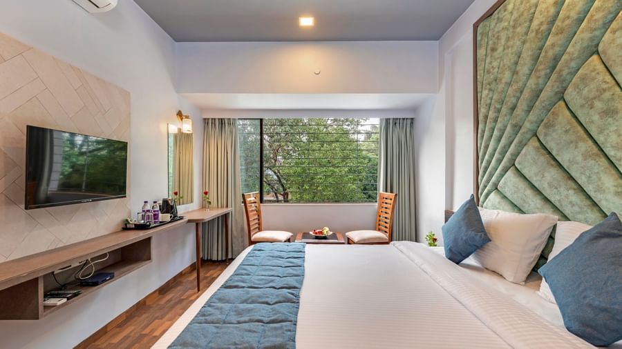 Spacious room at Emerald Retreat, Tungarli with a double bed, cushioned headboard, a work desk & chair, and a large TV unit.