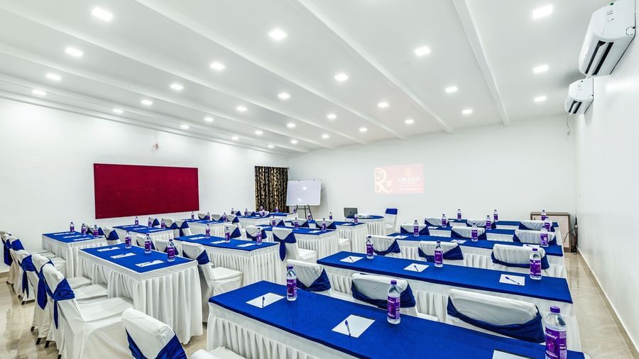Back side view of spacious banquet hall with multiple table rows arranged in classroom setting at Emerald Retreat, Tungarli.