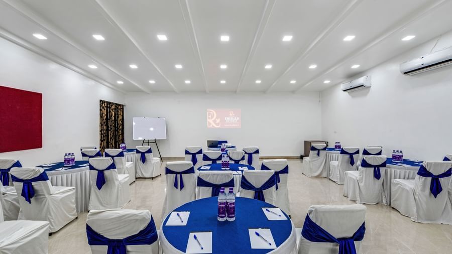 Elegant indoor event setup with banquet tables and presentation screen at Emerald Retreat, Tungarli.