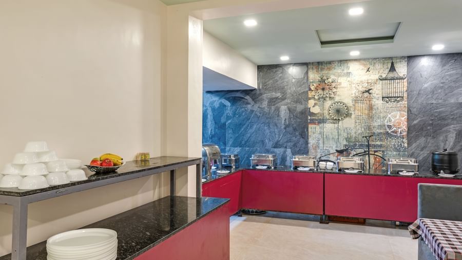 Buffet counter setup with white ceramics and steel utensils in the dining area at Emerald Retreat, Tungarli.