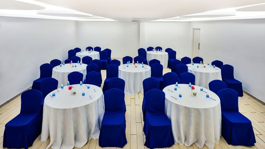 Rows of round banquet tables with white covers and blue chair sashes at Grande Bay Resort & Spa.