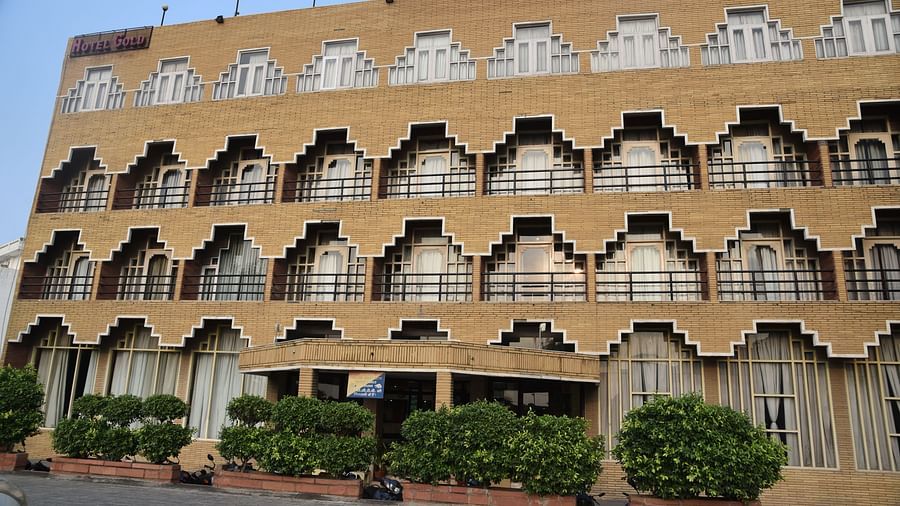 Exterior shot of Hotel Gold, Panipat taken in the morning with dense green bushes in the entrance.